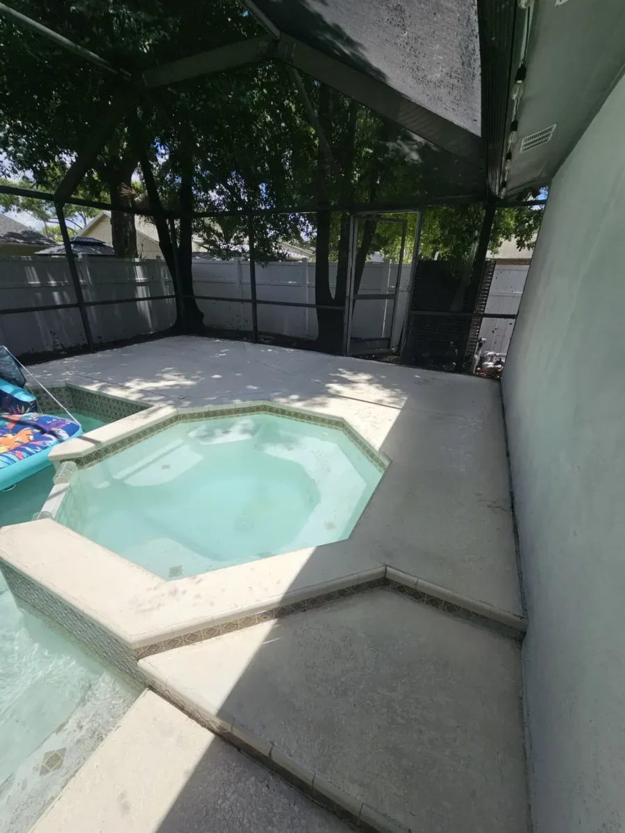 Let Us Restore Your Outdoor Living Space Empty backyard pool and spa area enclosed with screened fencing and surrounded by concrete patio