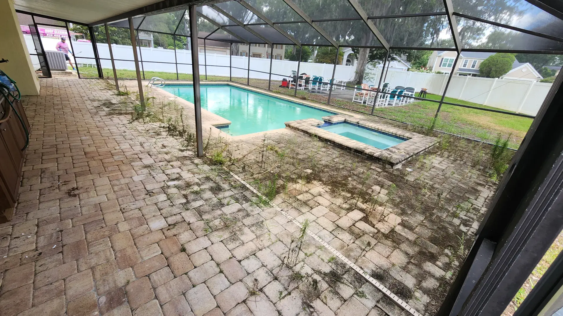 Let Us Restore Your Outdoor Living Space Weeds and dirt covering stone patio around screened-in pool and spa needing cleaning service